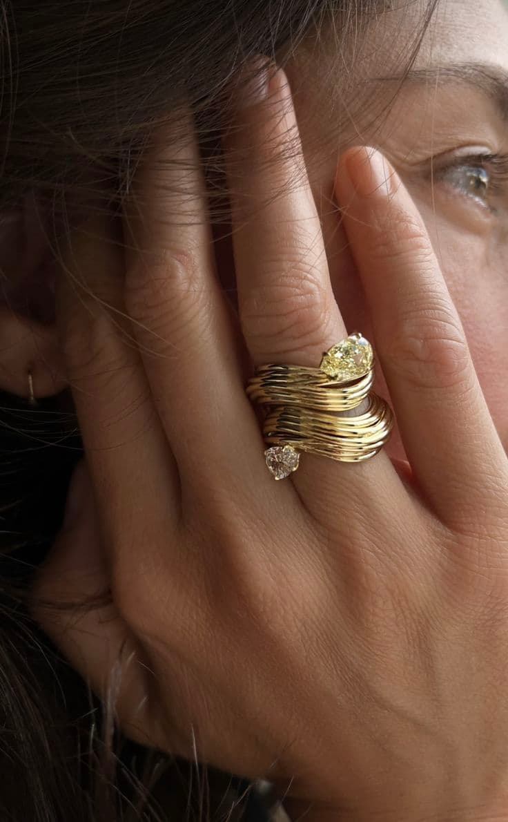 A hand wearing stacked gold rings set with pale diamonds